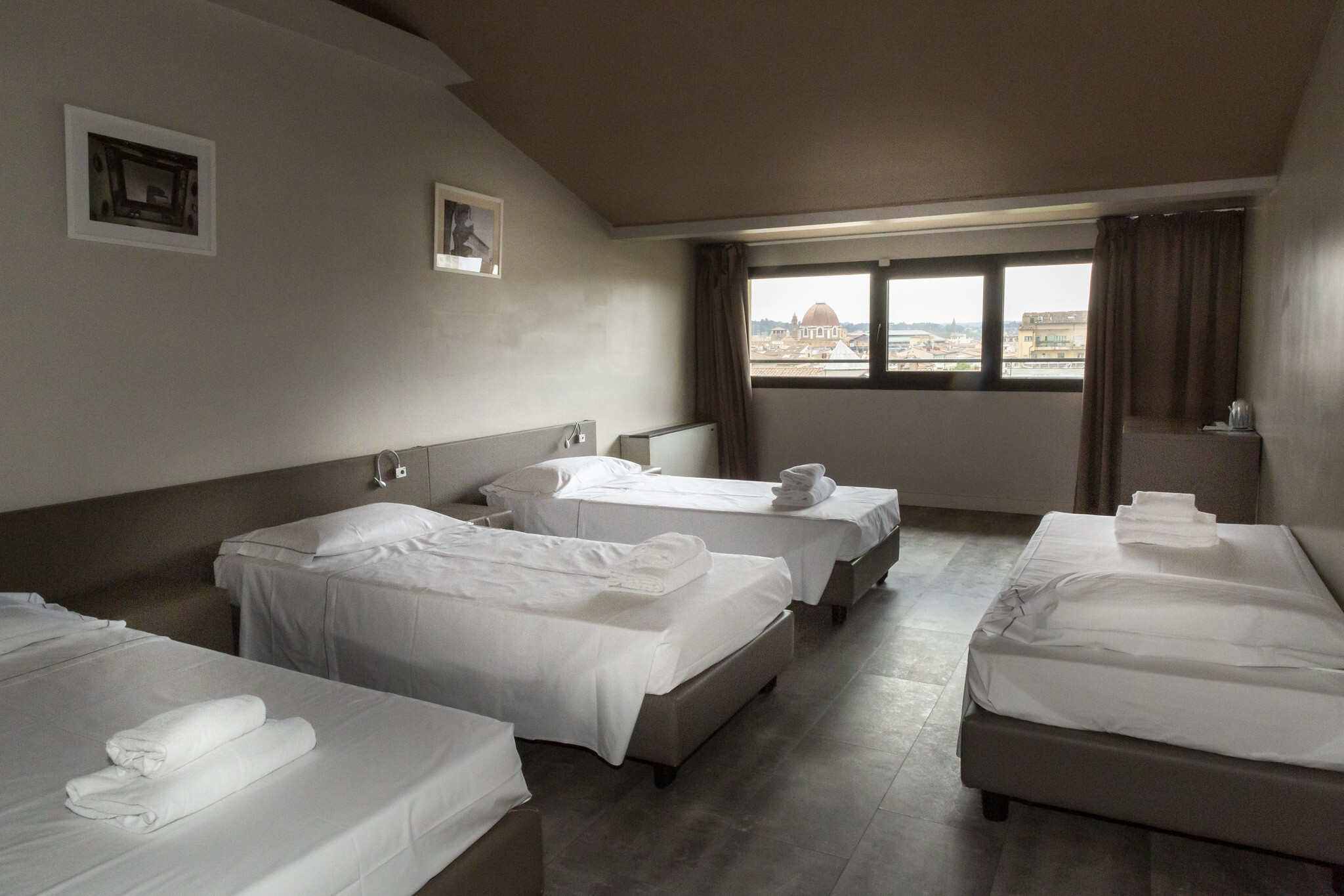 Quadruple room at Ostello Plus with four single beds.